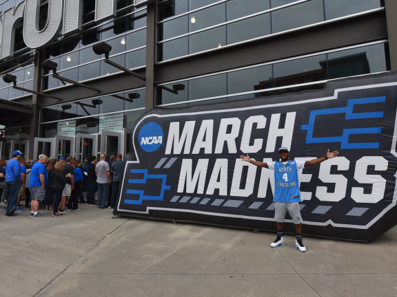 man poses with march madness sign