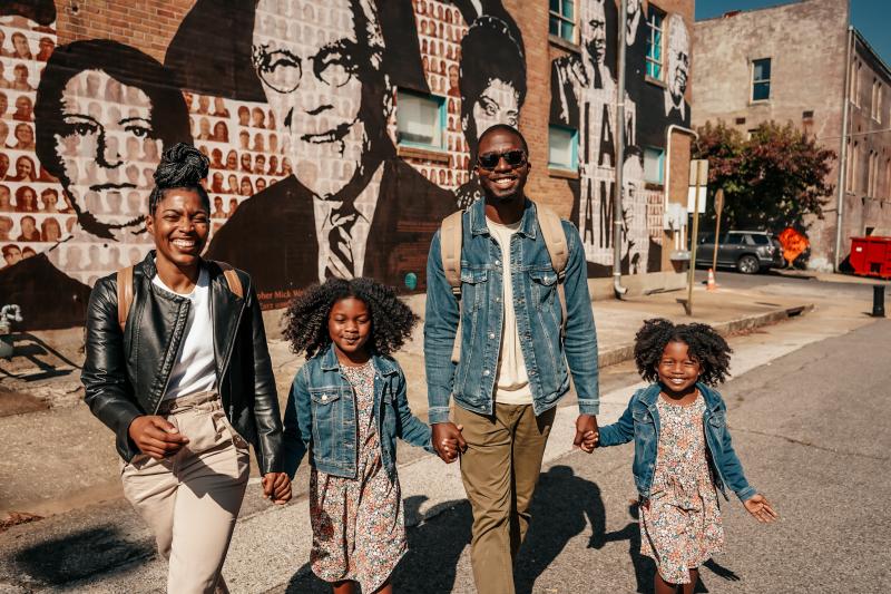 family of four walks towards camera in front of mural of historical memphis people