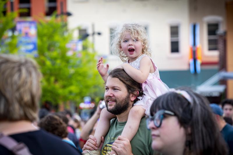 dad holding toddler daughter on shoulders during concert