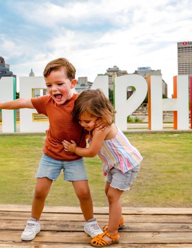 two children on Mud Island River Park pose in front of large Memphis letters