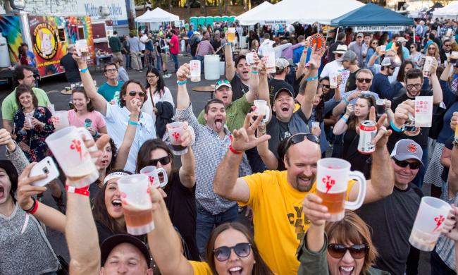 An excited crowd raising glasses at Cooper Young Beerfest