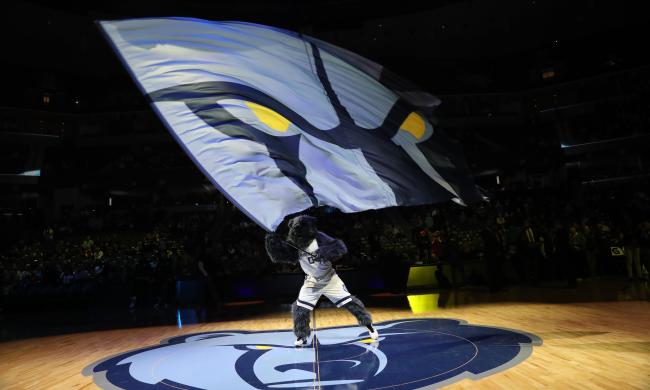 Grizz waving Memphis Grizzlies flag at an NBA basketball game.