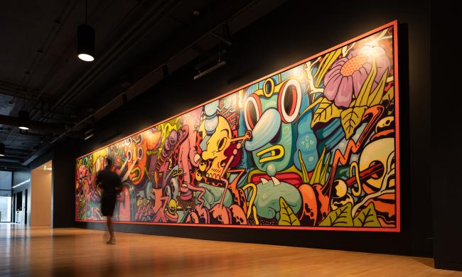 person walks in front of a large, wall covering mural by the artist Birdcap