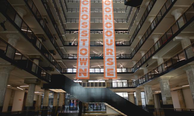 Orange and white Crosstown Concourse banners hanging vertically inside Crosstown Concourse.