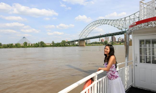 A passenger enjoying a sightseeing riverboat tour with Memphis' Pyramid and Hernando de Soto bridge in the background