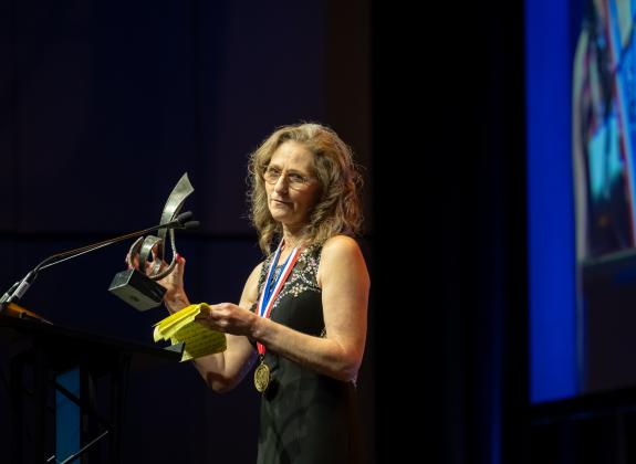 Woman holds up trophy at MSHOF on stage